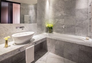 A modern bathroom with a freestanding bathtub, a marble sink, and a large mirror.