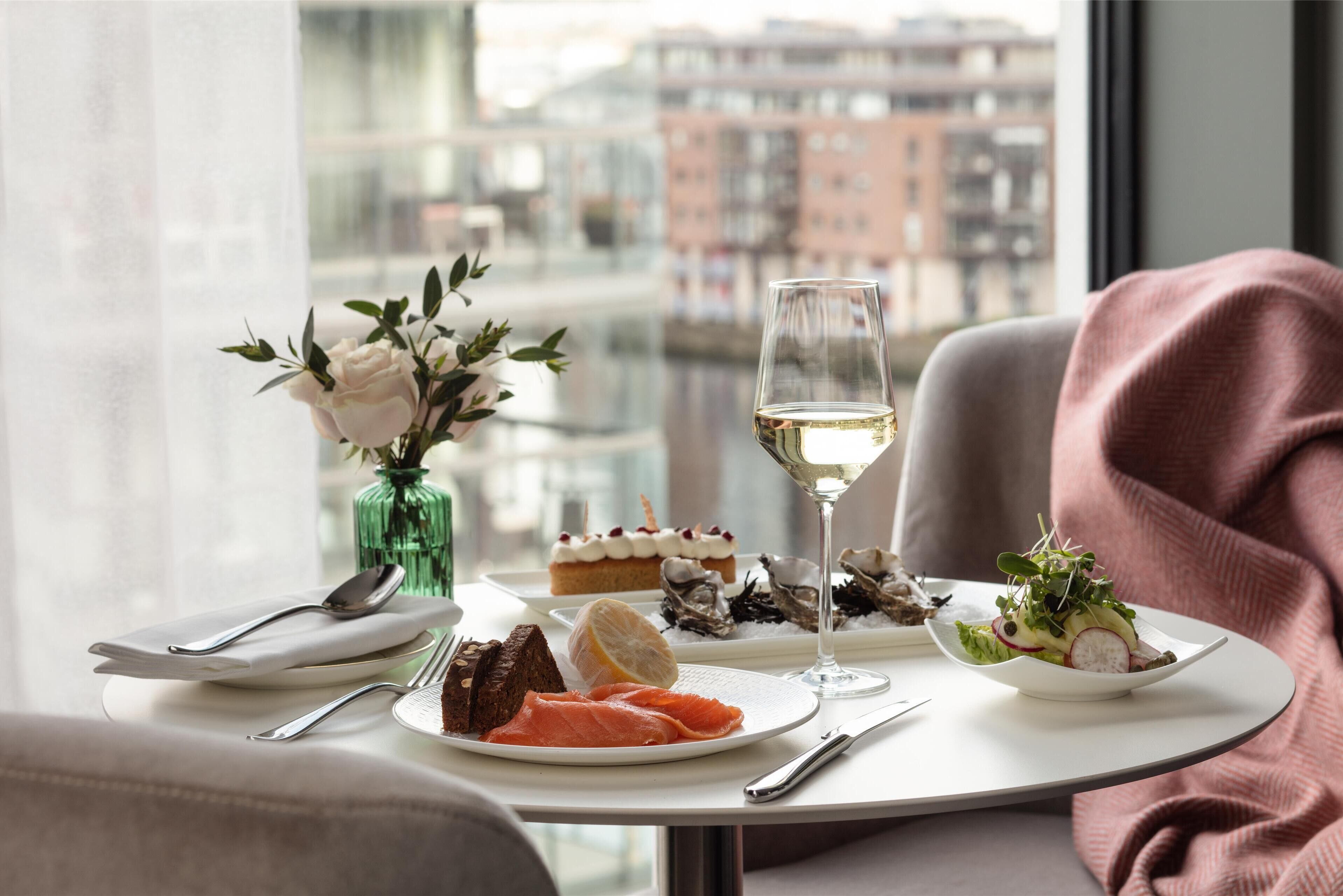 A dining table with plates of food, a glass of wine, and a vase of flowers.