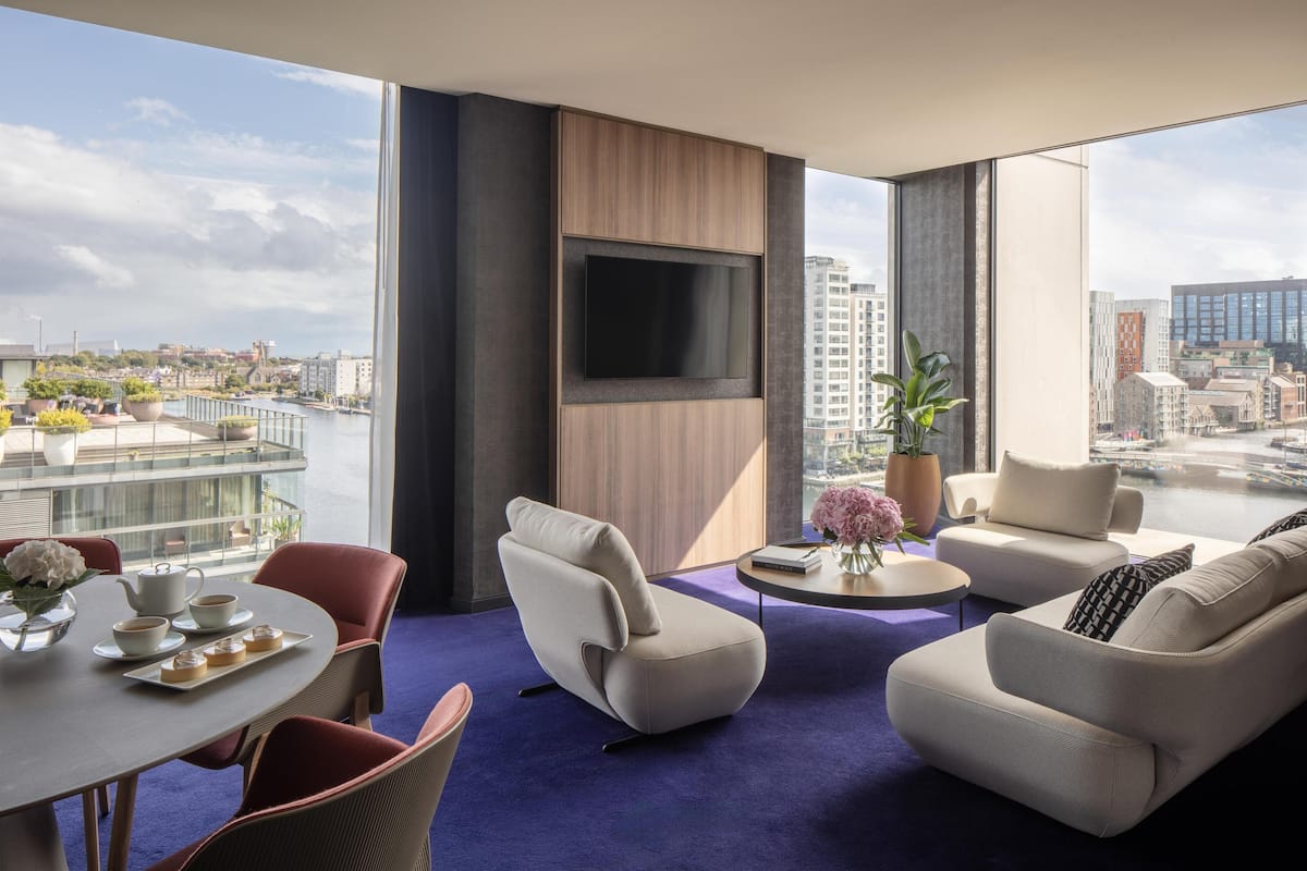 Una sala de estar moderna con vistas a la ciudad, un televisor de pantalla plana y un comedor con una mesa dispuesta para dos personas.