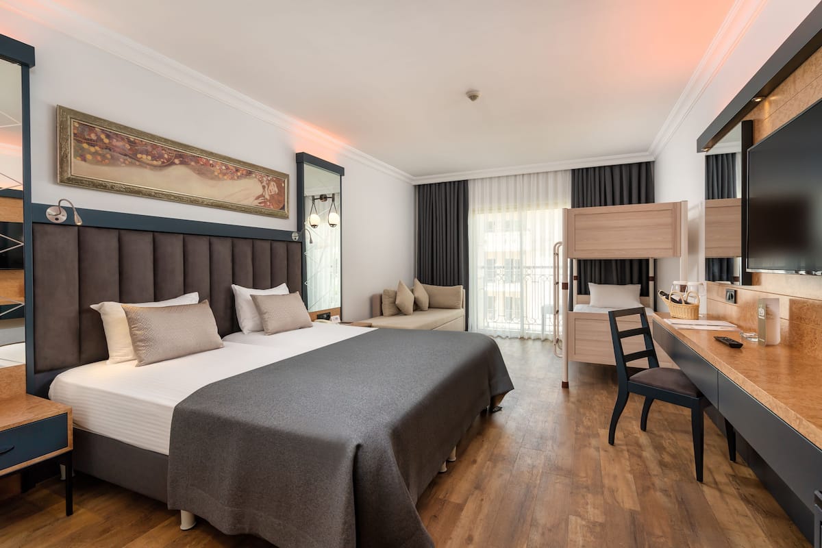 A modern hotel room with a large bed, a desk, and a seating area.