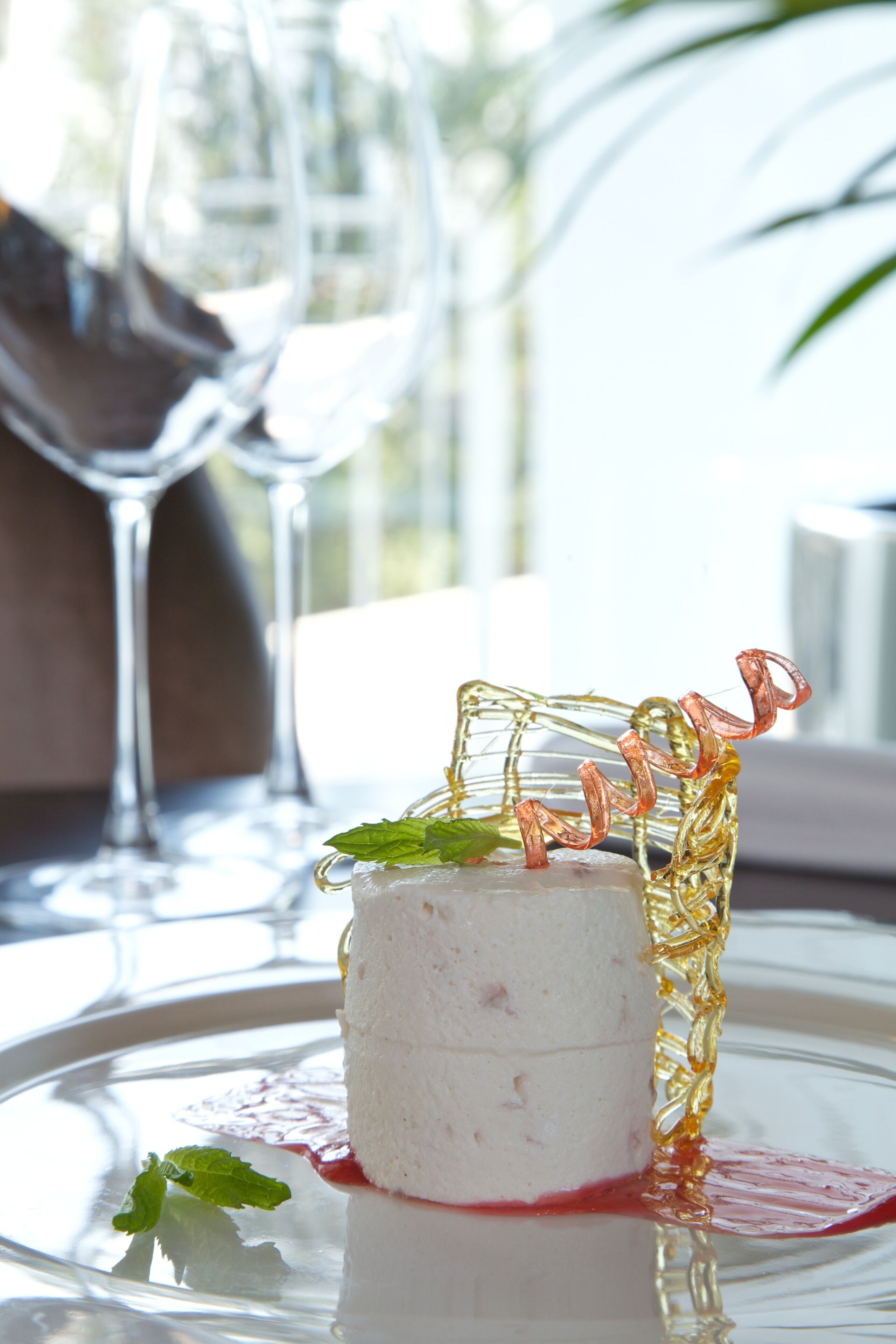A dessert on a glass plate with a clear glass and a decorative glass piece.