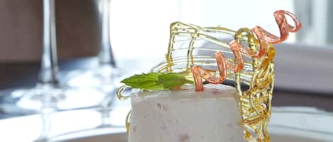 A dessert on a glass plate with a clear glass and a decorative glass piece.