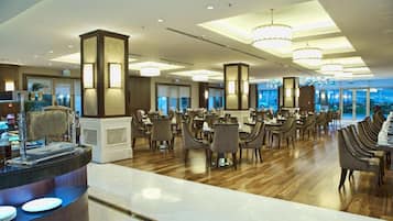 A spacious restaurant with high ceilings, modern chandeliers, and a long counter with seating.