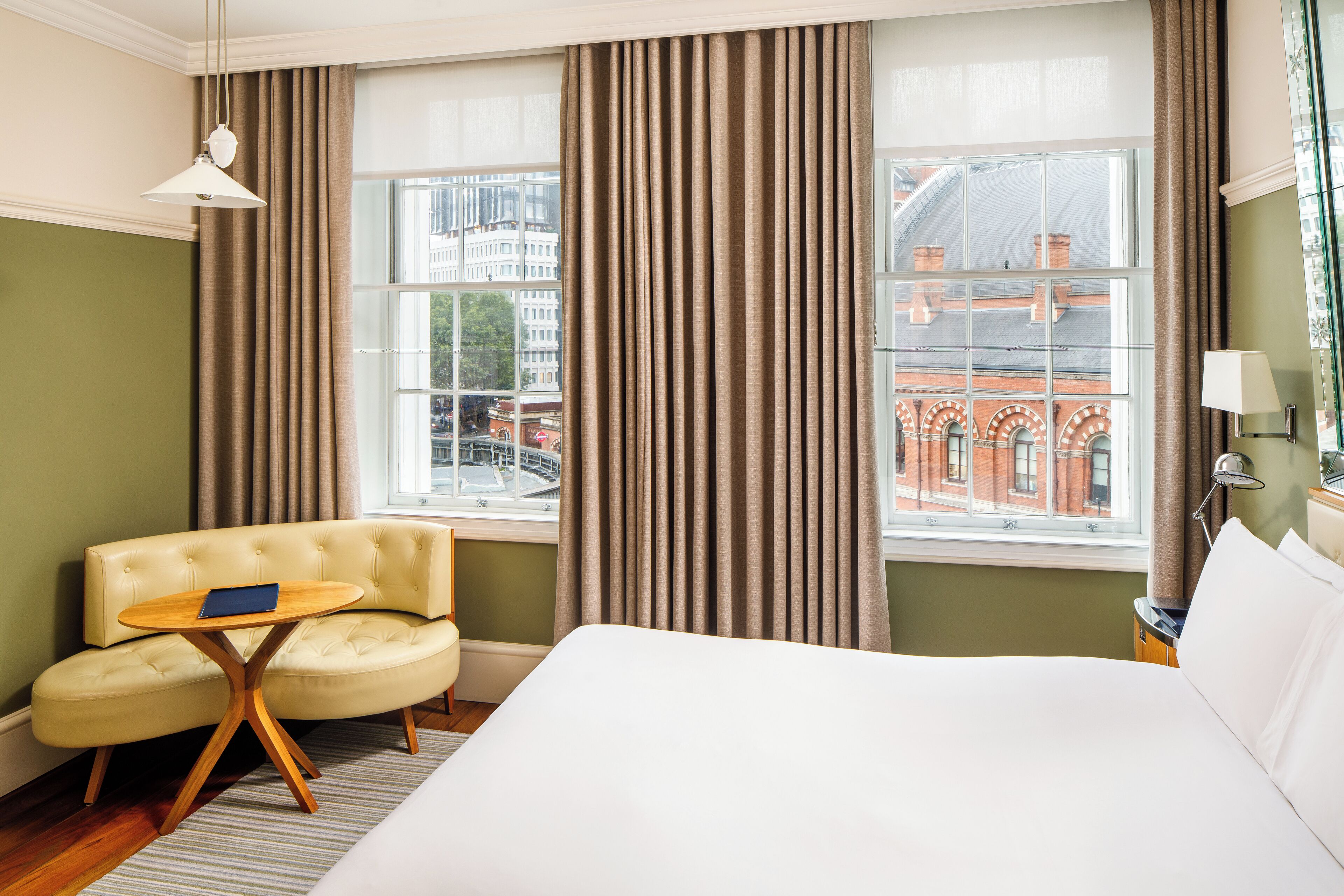 Ein Hotelzimmer mit einem Bett, einer Couch, einem kleinen Tisch und einem Fenster mit Vorhängen.