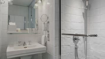 Ein modernes Badezimmer mit Duschkabine aus Glas, einem Waschbecken mit Spiegel und einem Handtuchhalter.