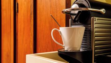 A coffee machine with a cup and a spoon on a tray.