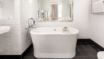 A modern bathroom with a freestanding bathtub, a glass shelf, and a large mirror.