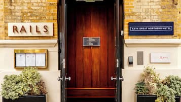 A hotel entrance with a wooden door, signs for 'RAILS Restaurant & Little Bar' and 'KAYA GREAT NORTHERN HOTEL', and a sign indicating the hotel's reception and bar locations.
