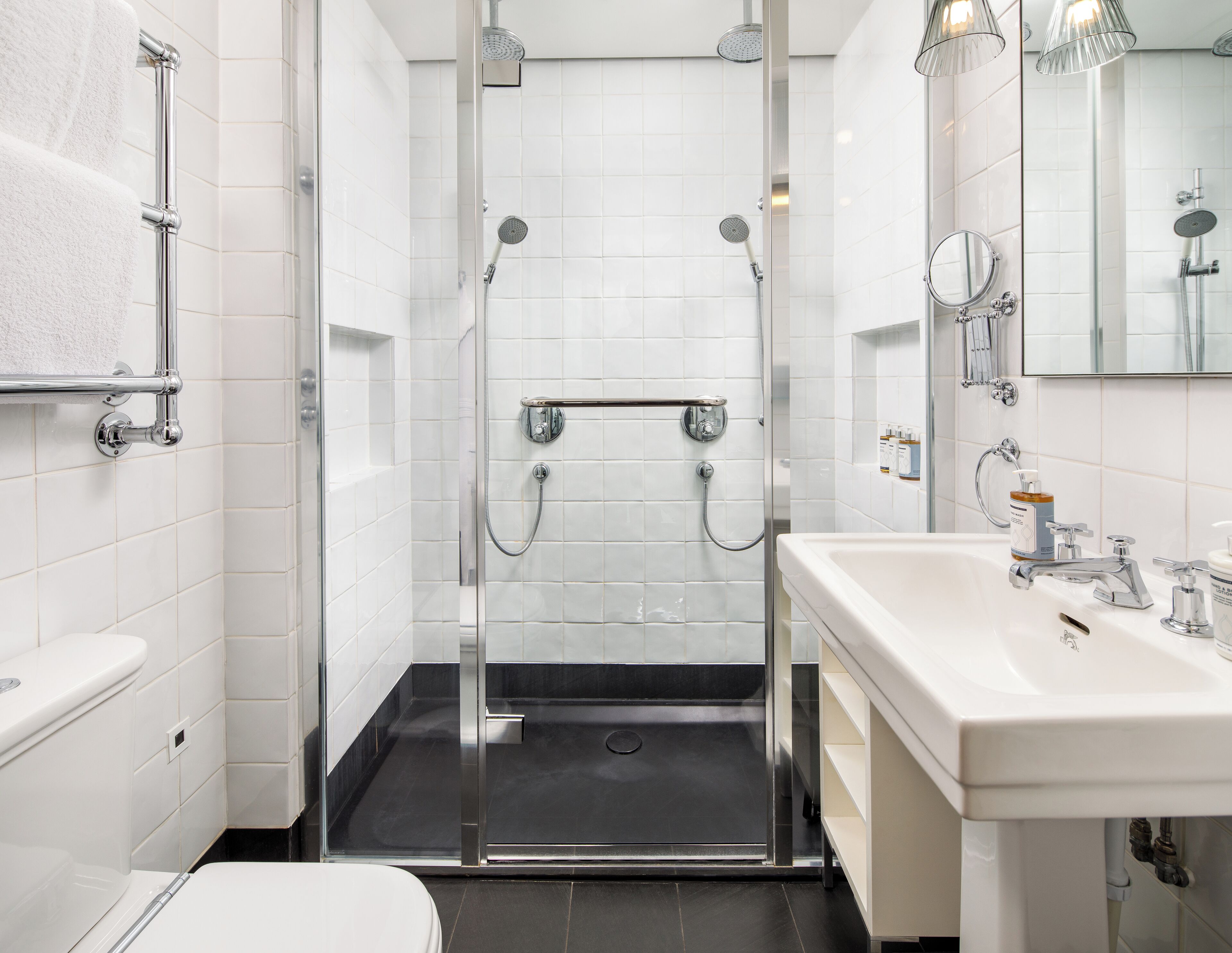 Un baño moderno con ducha de vidrio, lavamanos blanco con espejo y un inodoro.