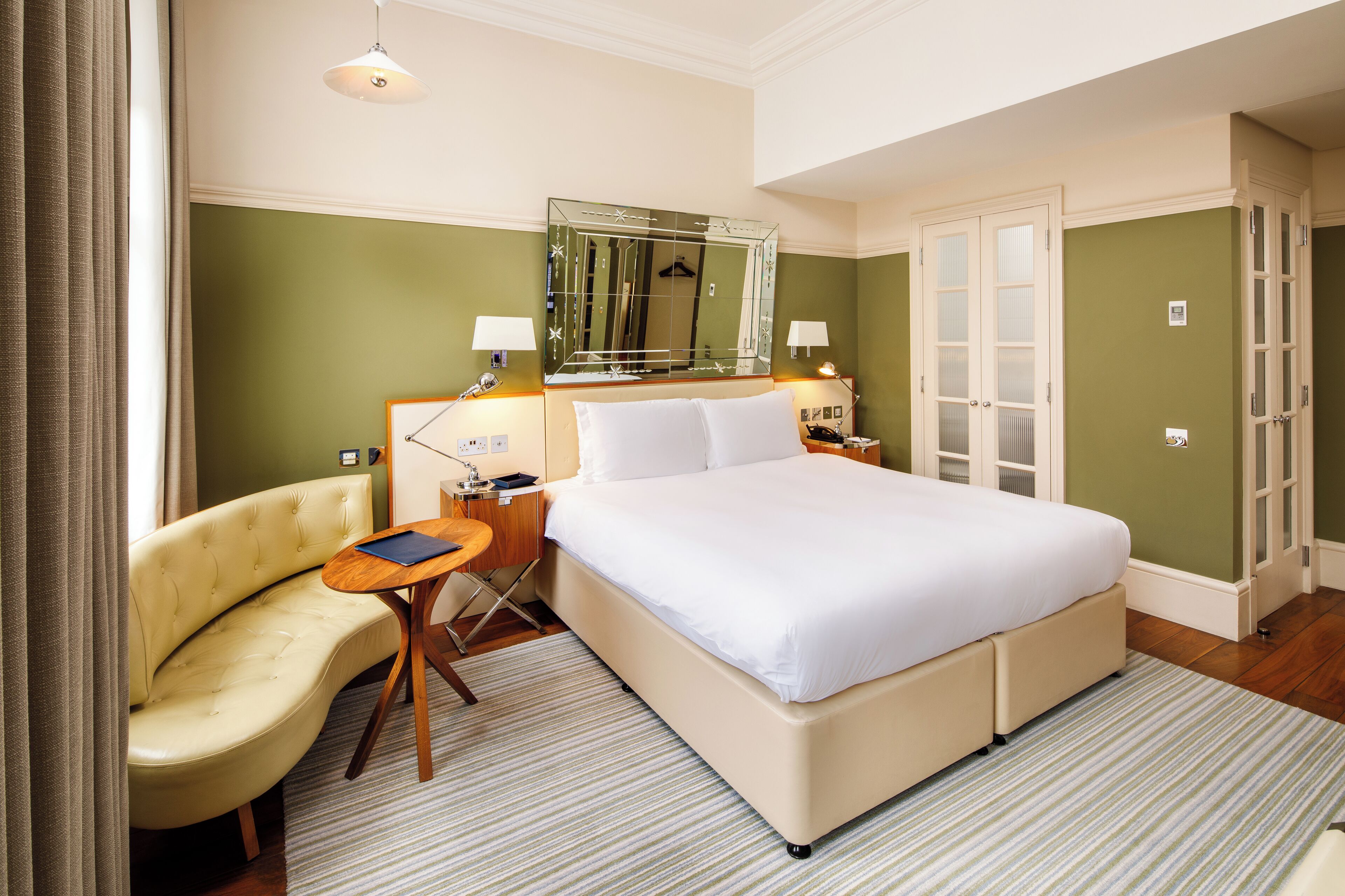 Une chambre d’hôtel avec un grand lit, un canapé, un bureau et un miroir.