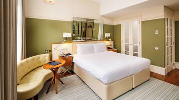 Une chambre d’hôtel avec un grand lit, un canapé, un bureau et un miroir.
