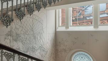 A staircase with ornate metal railings and a geometric wall mural.