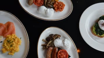 Tre piatti di cibo con diversi piatti, tra cui salsicce, pomodori e funghi.