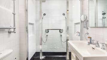 A modern bathroom with a glass-enclosed shower, a white sink with a mirror, and a towel rack.