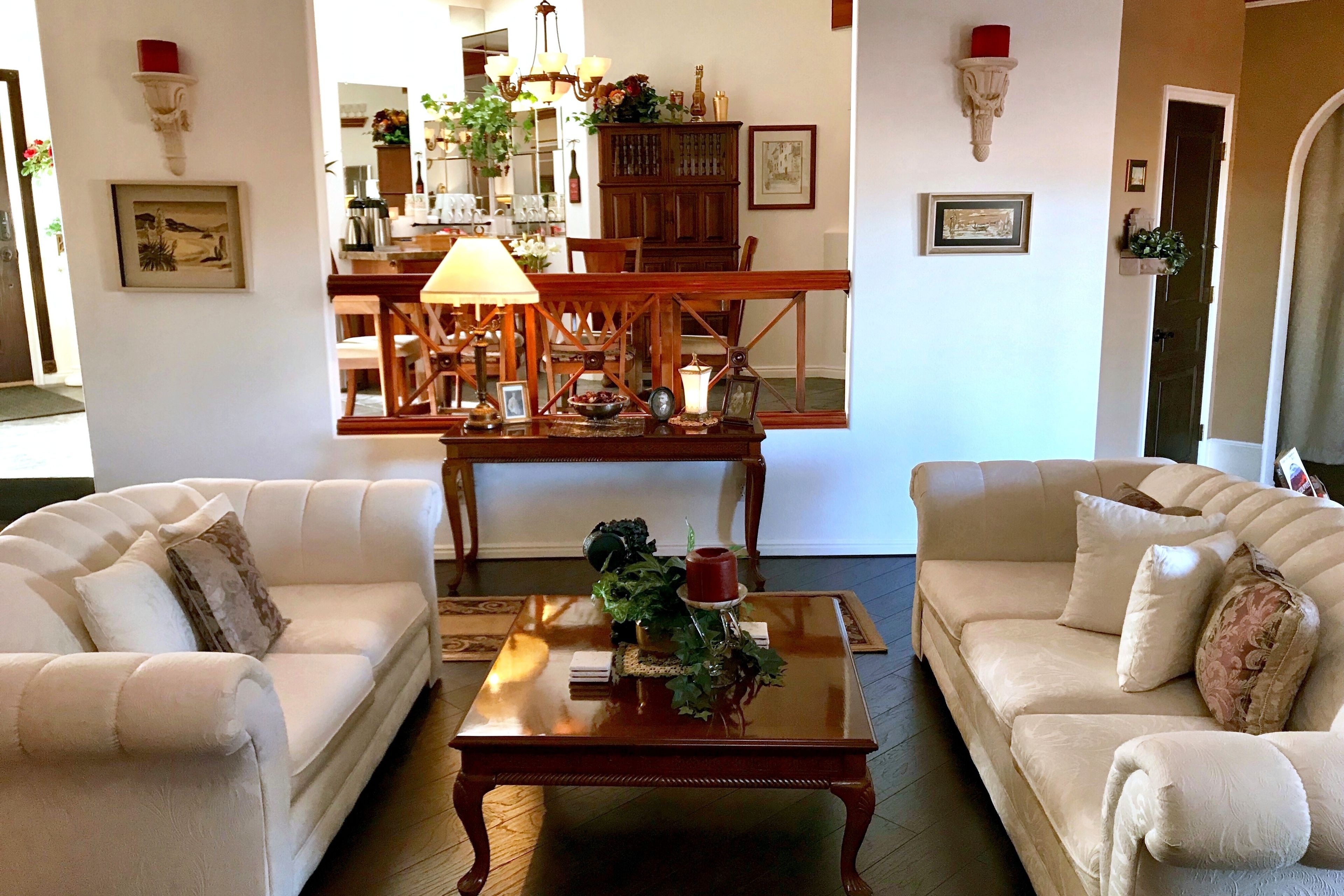 A living room with two sofas, a coffee table, and a dining area with a chandelier.