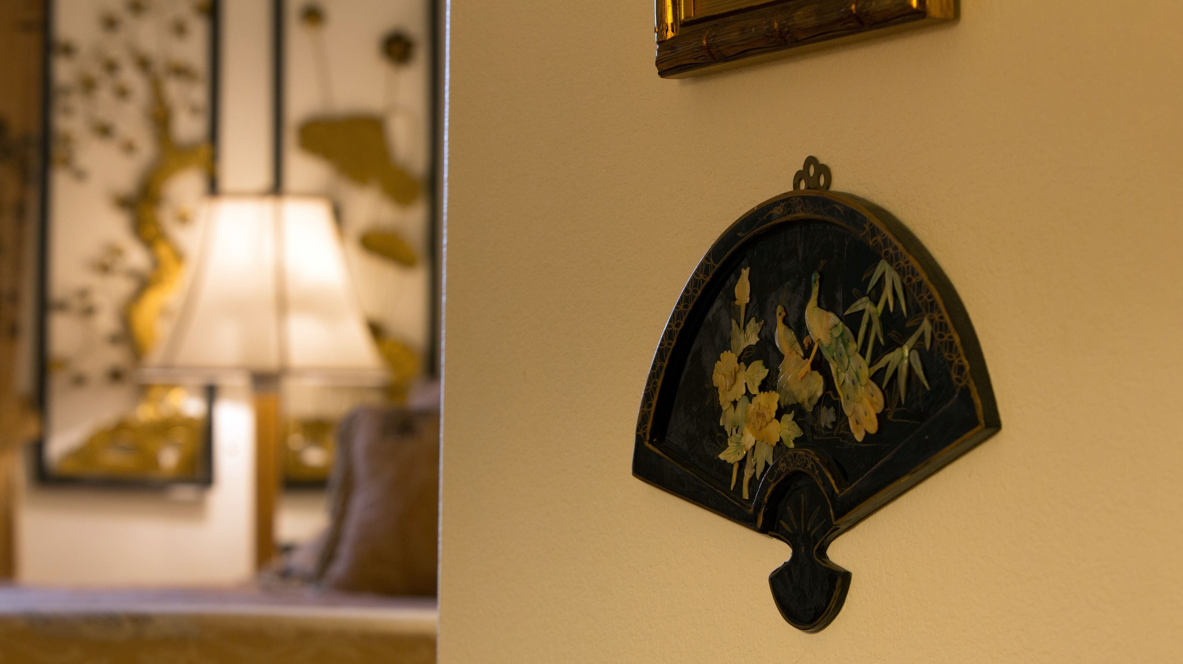 A wall-mounted decorative piece with a peacock and floral design.