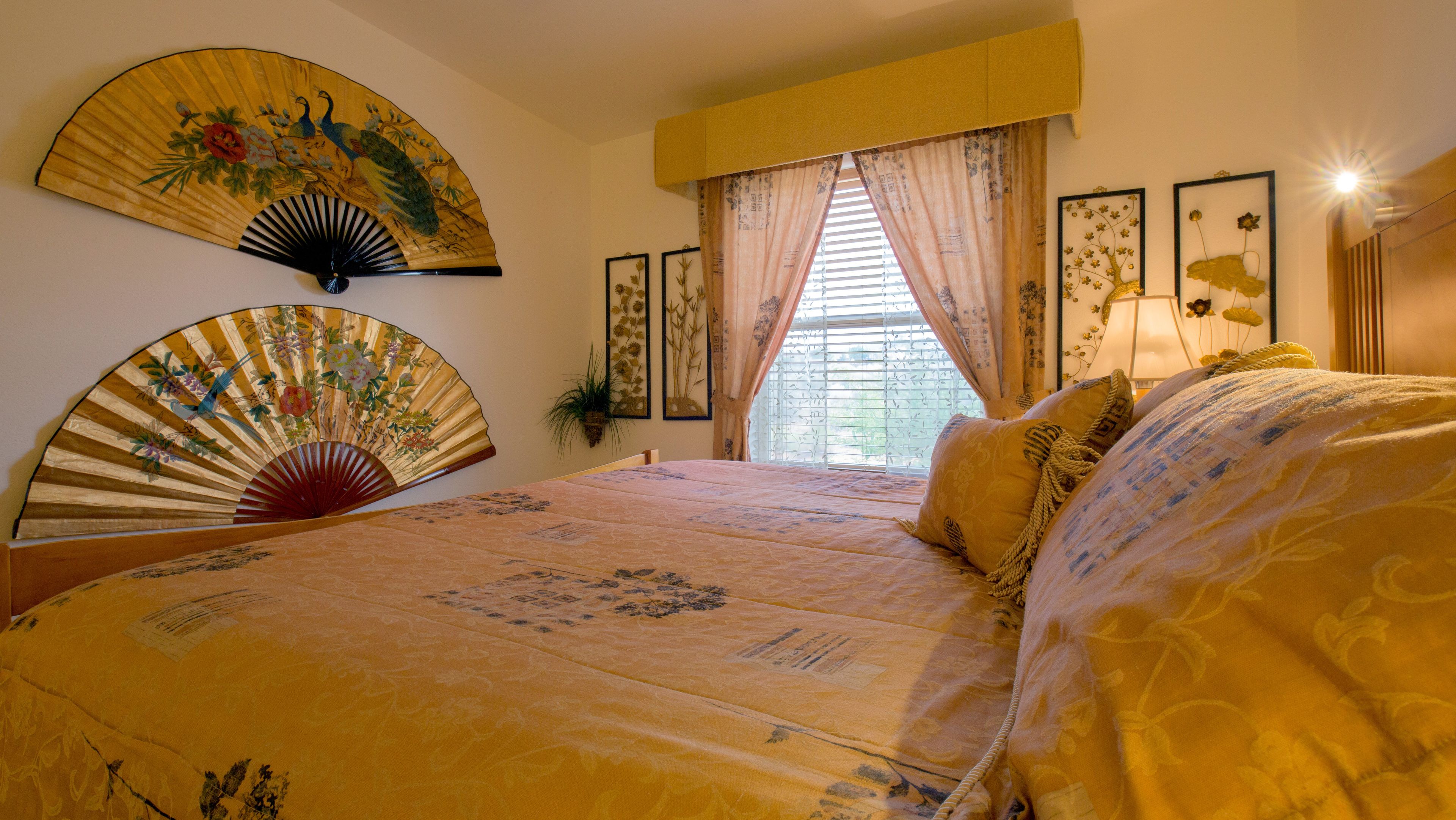 Un dormitorio con una cama grande, dos ventiladores de pared y un ventanal con cortinas.