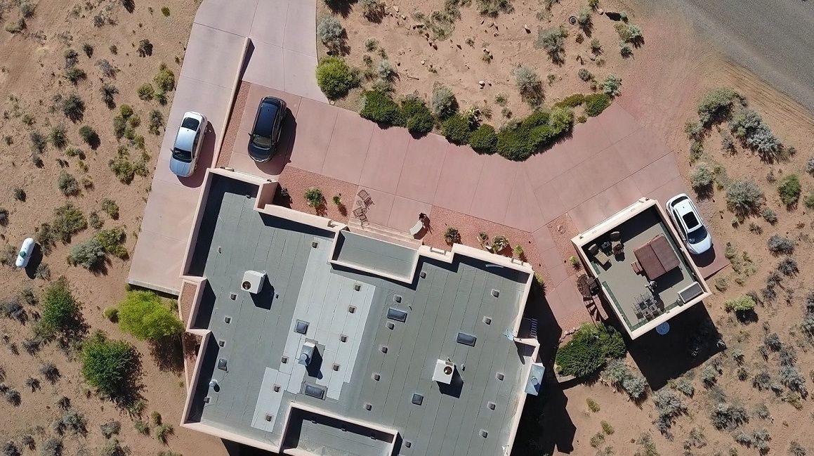 Vue aérienne d’un bâtiment doté d’un toit plat, de nombreux espaces de stationnement et d’un espace paysager avec une végétation clairsemée.