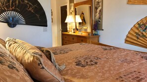 Un dormitorio con cama, cómoda, espejo y ventilador.