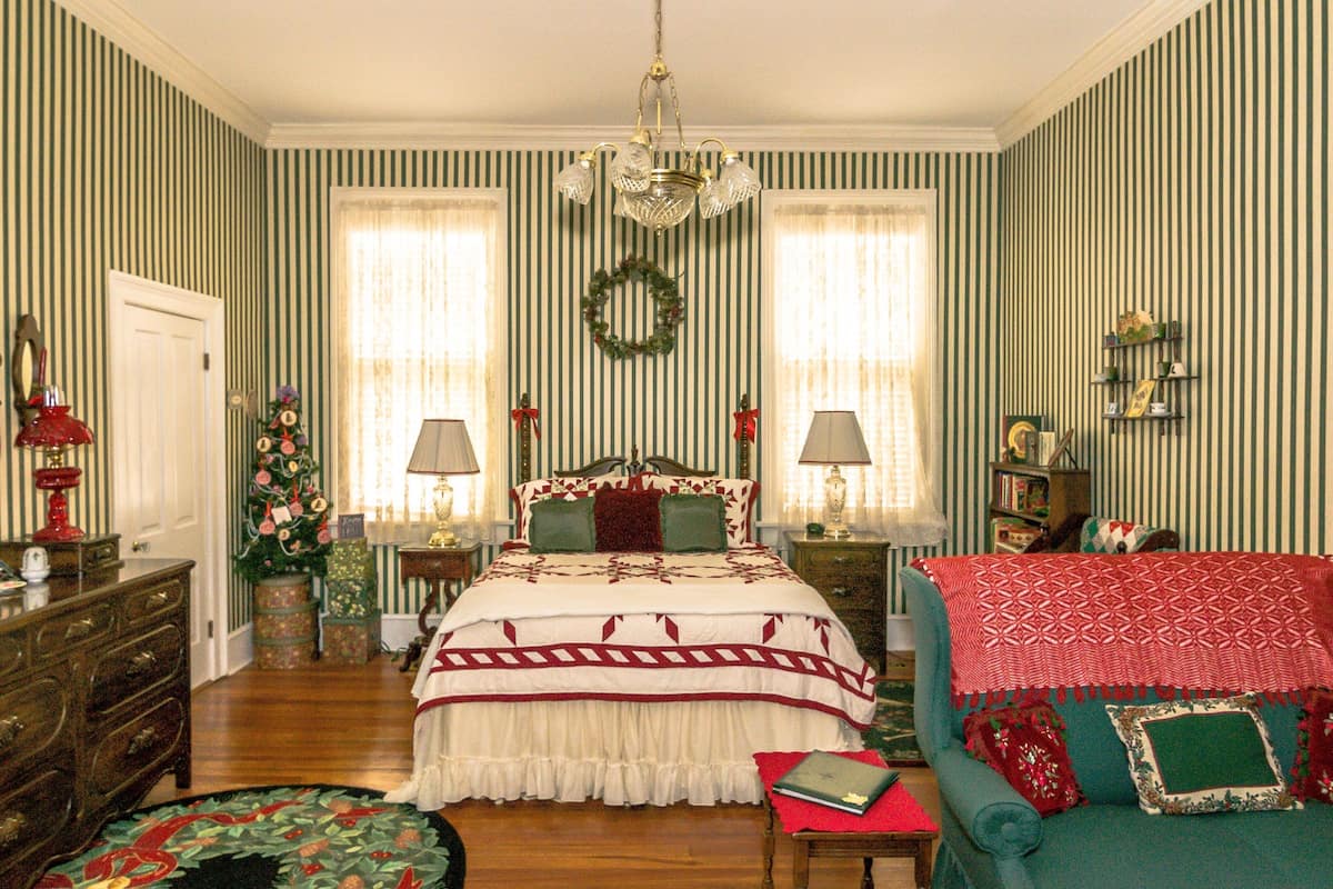 A room with a bed, two lamps, a dresser, a chair, and a small table.