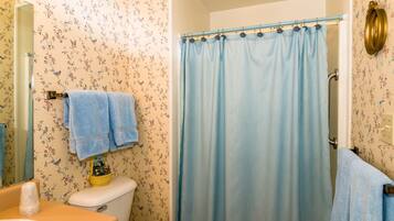 Een badkamer met bloemenbehang, een toilet, een wastafel en een douchegordijn.