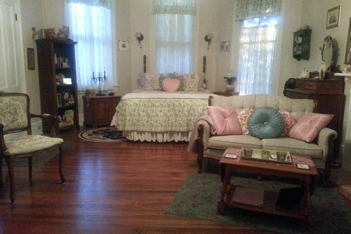A cozy living room with a floral-patterned sofa, a wooden coffee table, and a vintage armchair.