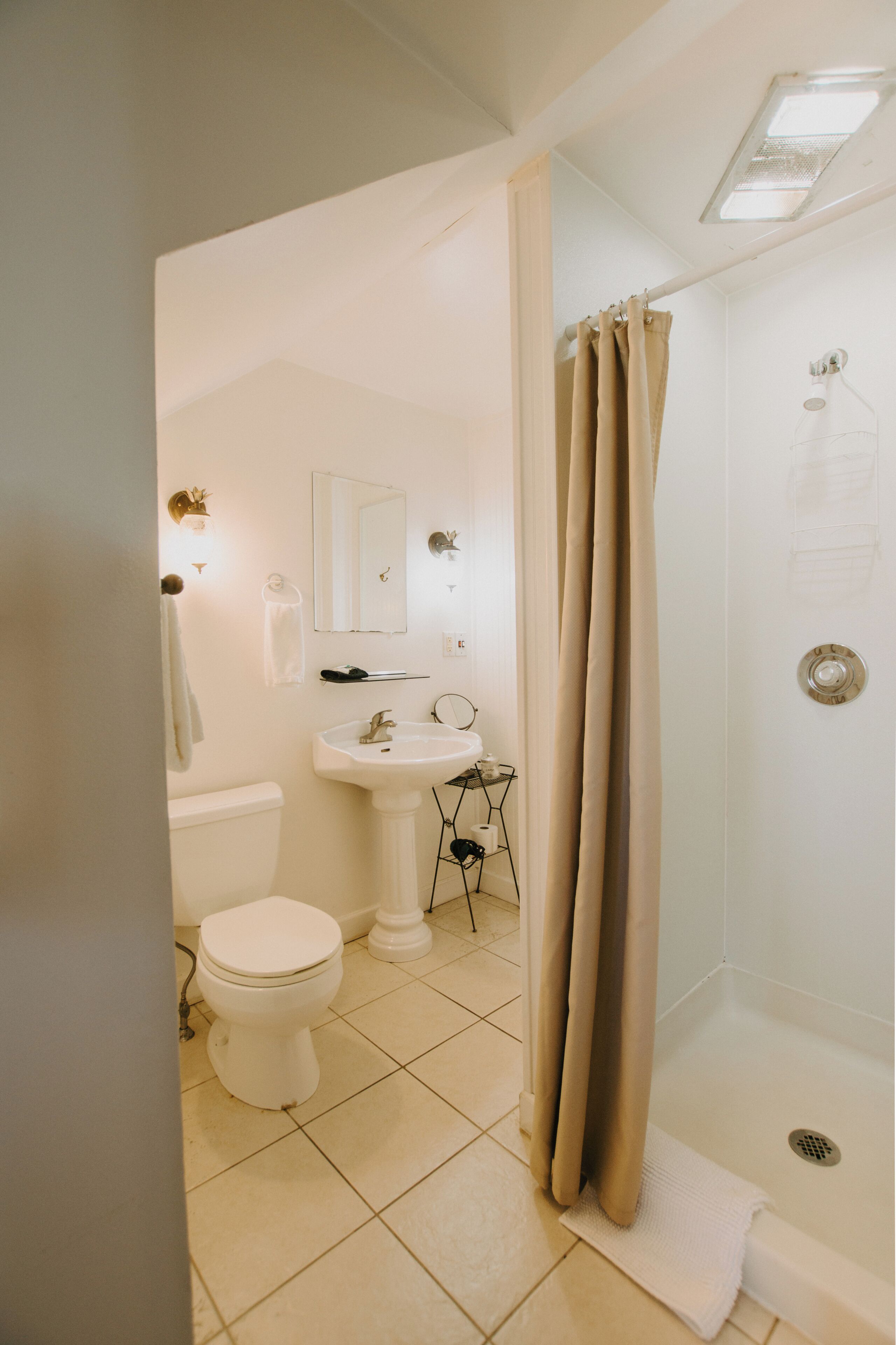 A bathroom with a toilet, sink, mirror, and shower.