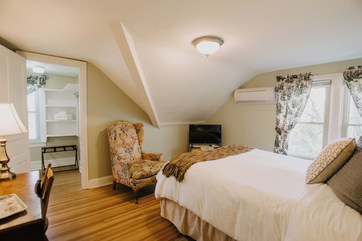 A bedroom with a bed, a chair, a TV, and a closet.