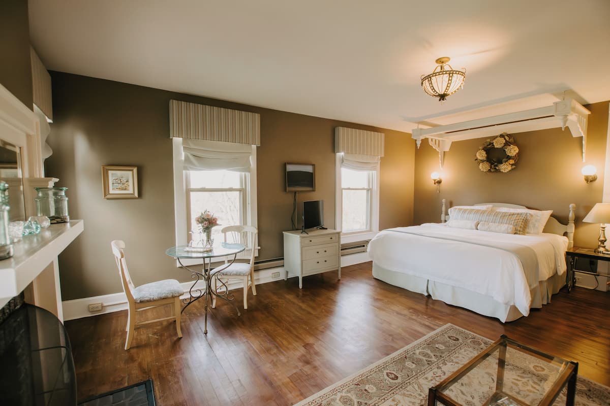 A bedroom with a bed, a desk, a chair, a television, and a window with curtains.