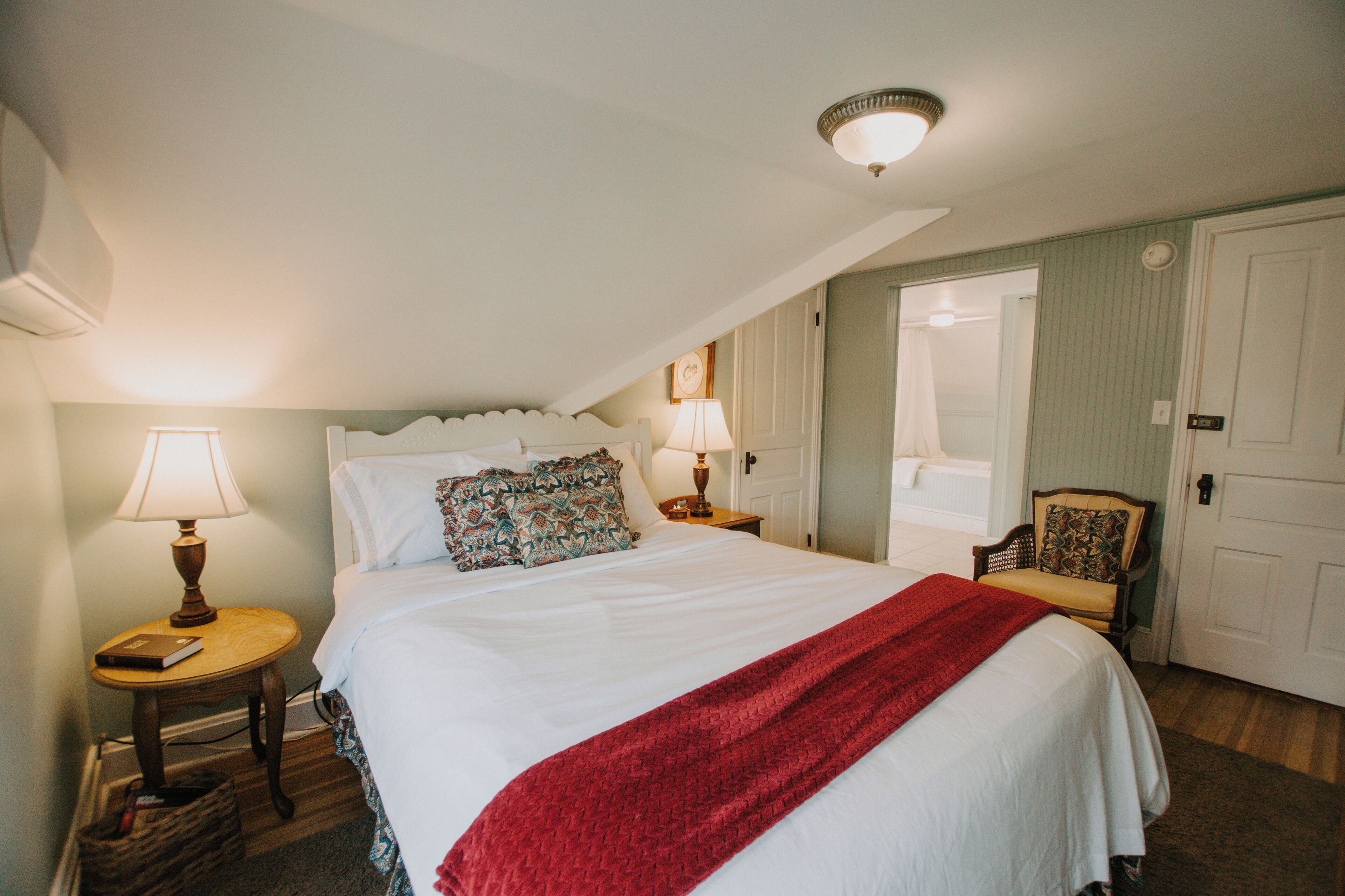 Une chambre à coucher avec un lit, deux tables de chevet, une chaise et une porte.