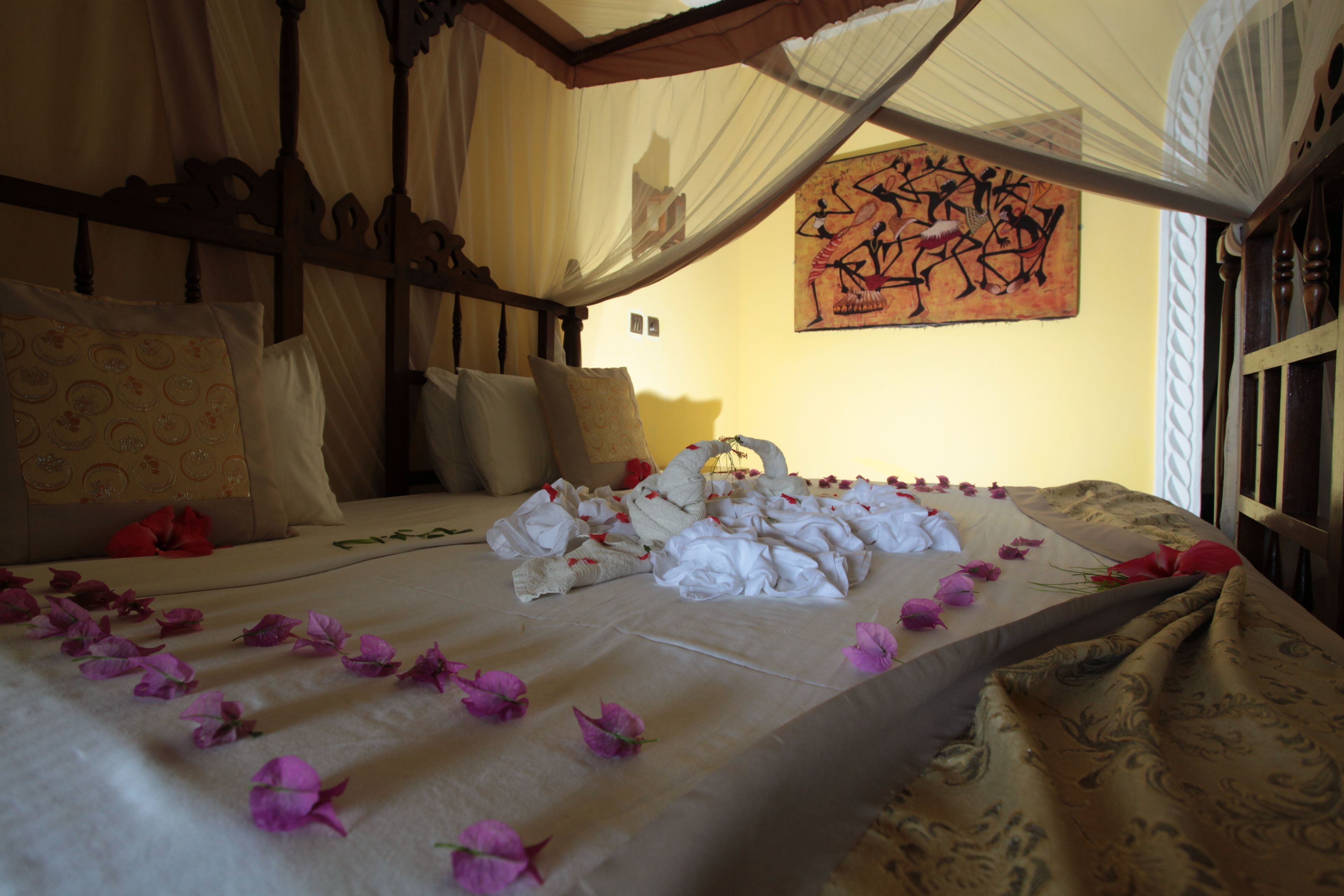 A bed with a canopy, pillows, and a blanket with flowers.