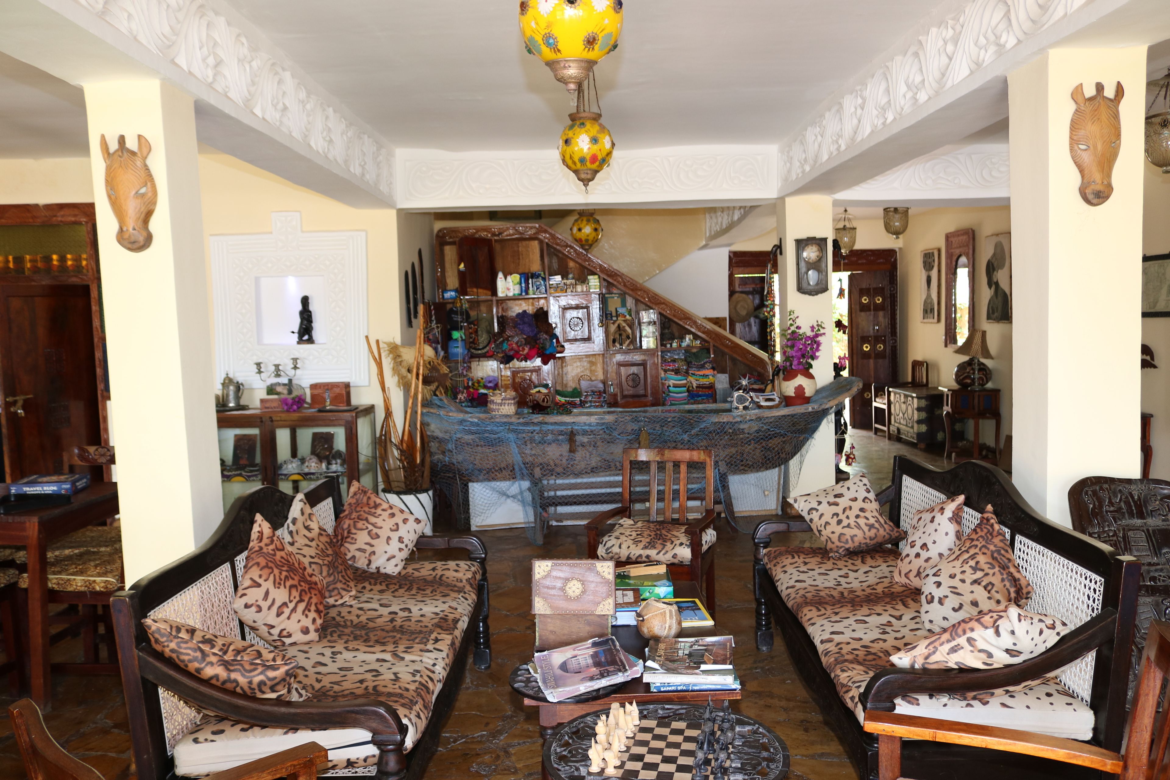 Uma sala de estar tradicional com sofás estampados, um tabuleiro de xadrez e uma escadaria que dá para um segundo andar.