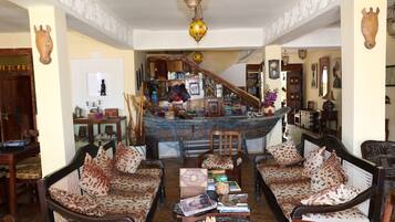 Uma sala de estar tradicional com sofás estampados, um tabuleiro de xadrez e uma escadaria que dá para um segundo andar.