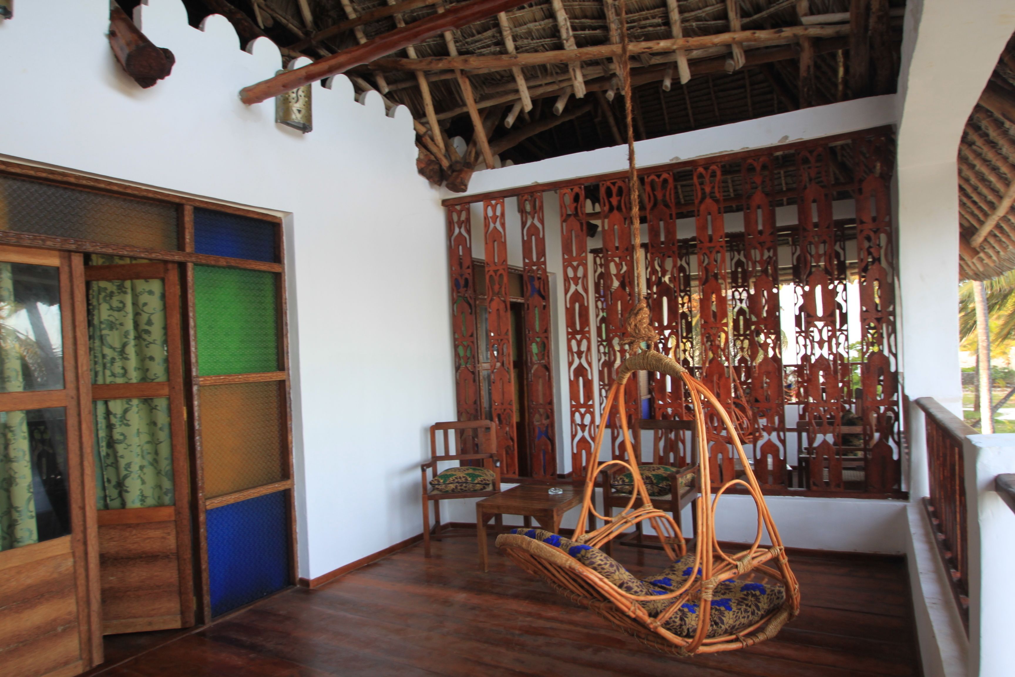 A traditional room with a wooden ceiling, a hanging chair, and a decorative wooden screen.