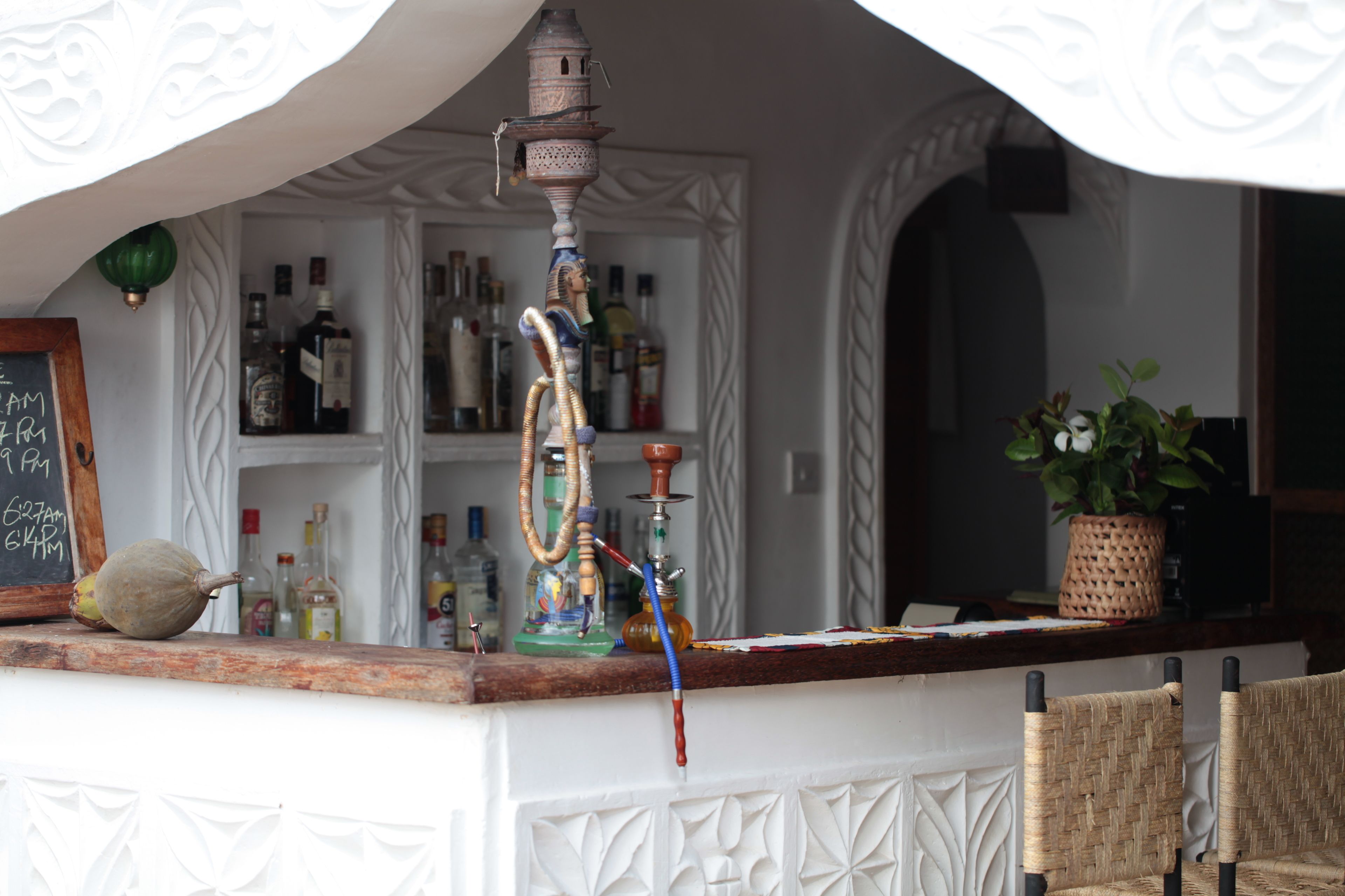 A bar area with a hookah, bottles, and a chalkboard menu.