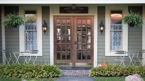 A house with a wooden front door, two windows with hanging plants, and a sign that reads "Home Sweet Home Prairie Guest House." - Prairie Guest House (Fishers)