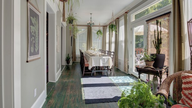 A dining area with a table set for four, surrounded by chairs, with hanging plants and a chandelier. - Prairie Guest House (Fishers)