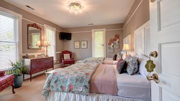 A bedroom with a bed, dresser, chair, and a television on the wall.