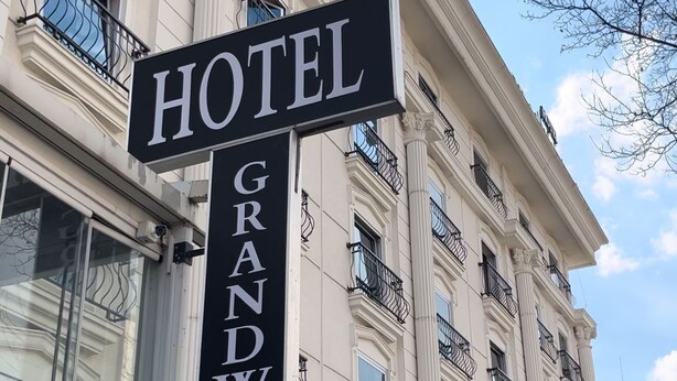 A hotel sign with "HOTEL GRANDWONE" written on it, attached to a building with classical architecture and multiple balconies.