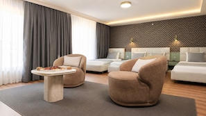 A modern hotel room with a sofa set, a round table with a plate of food, and a patterned wall.