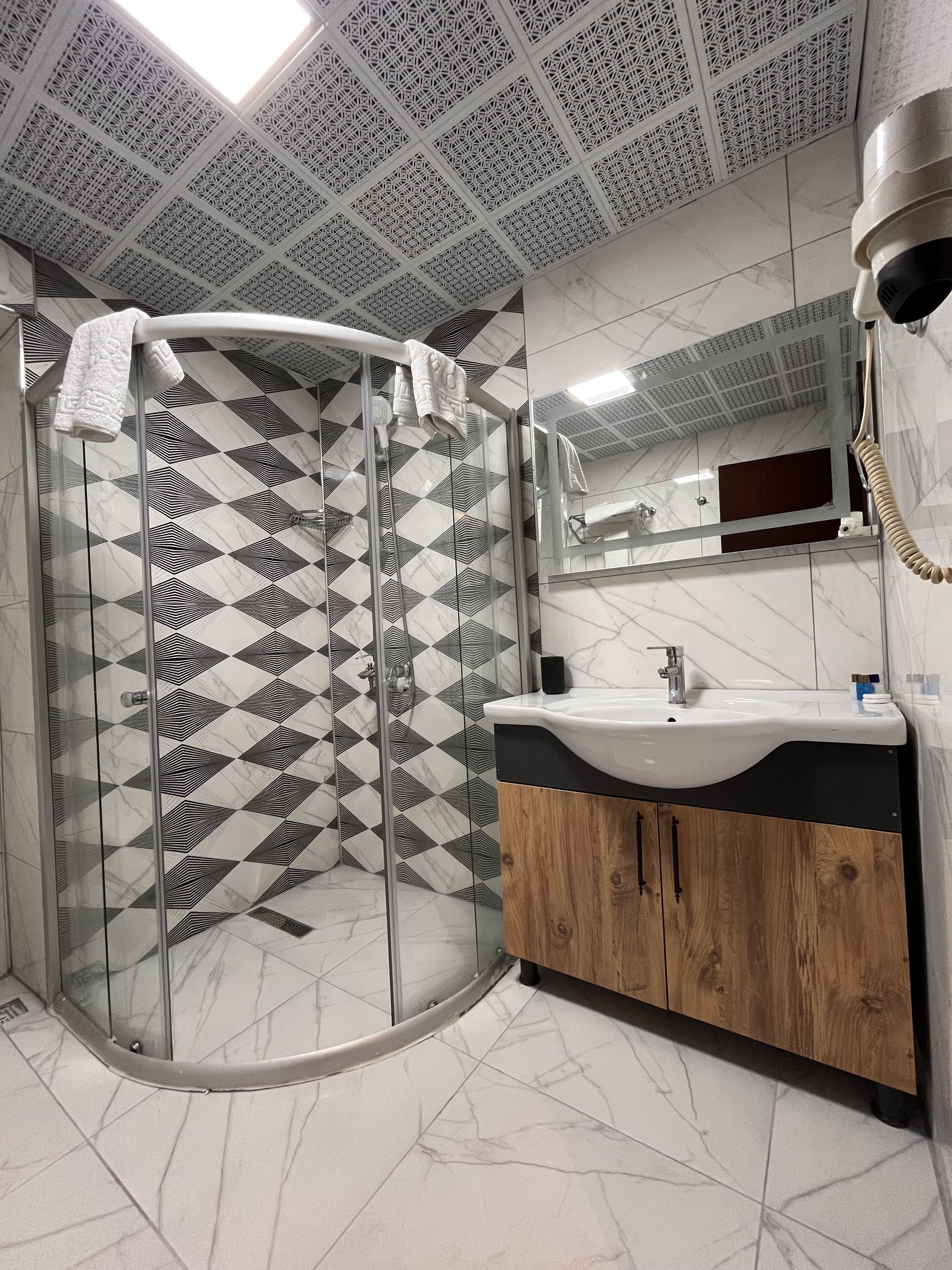 Un baño moderno con cabina de ducha de vidrio, un lavabo con mueble de madera y un espejo sobre el lavabo.