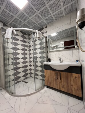 Un baño moderno con cabina de ducha de vidrio, un lavabo con mueble de madera y un espejo sobre el lavabo.