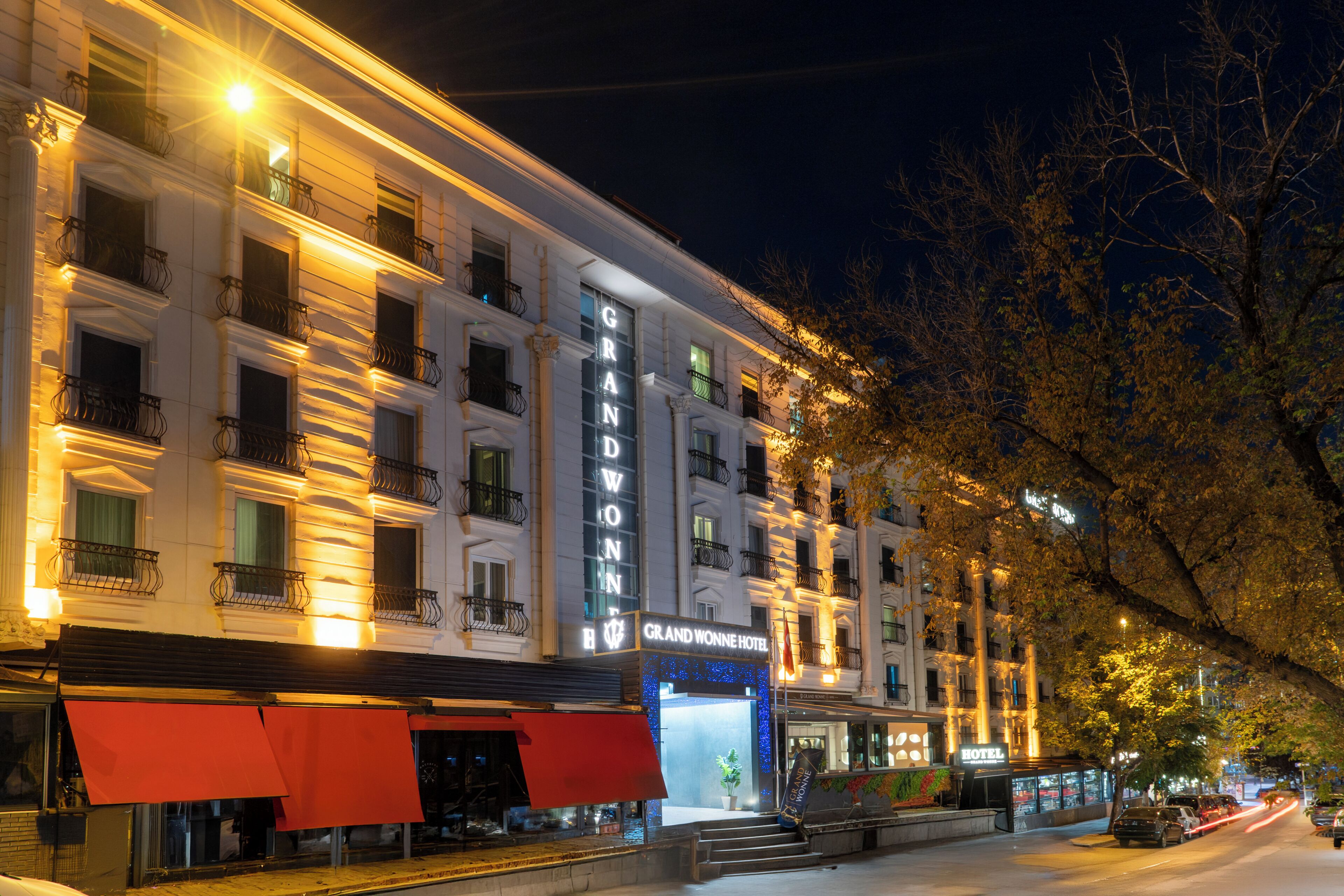 Un hotel de varios pisos con un letrero destacado, balcones y una entrada visible.