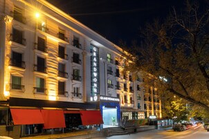 Un hotel de varios pisos con un letrero destacado, balcones y una entrada visible.