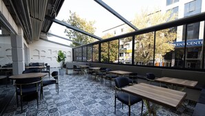 An outdoor seating area with patterned tiles, tables, and chairs, overlooking a building with a sign reading 'Kent Center.'