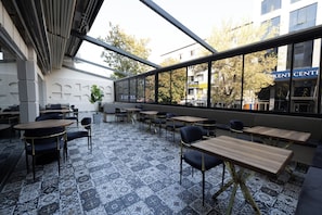 An outdoor seating area with patterned tiles, tables, and chairs, overlooking a building with a sign reading 'Kent Center.'