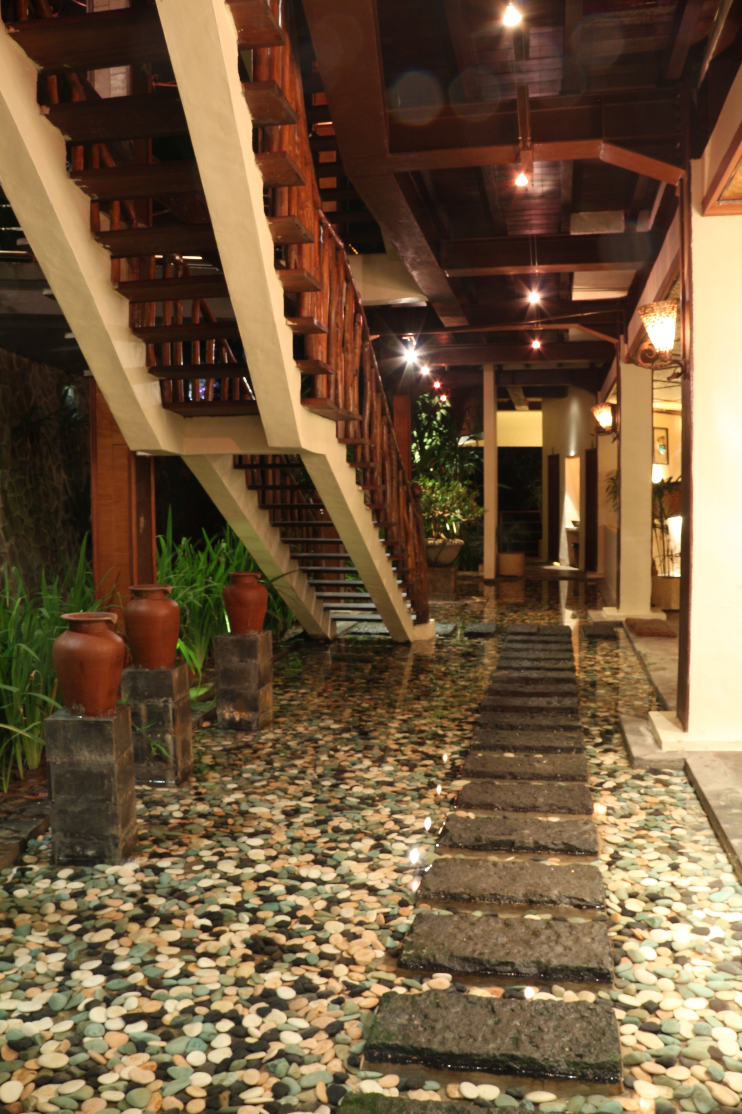 A stone pathway leading up a wooden staircase in a building with a tiled floor.