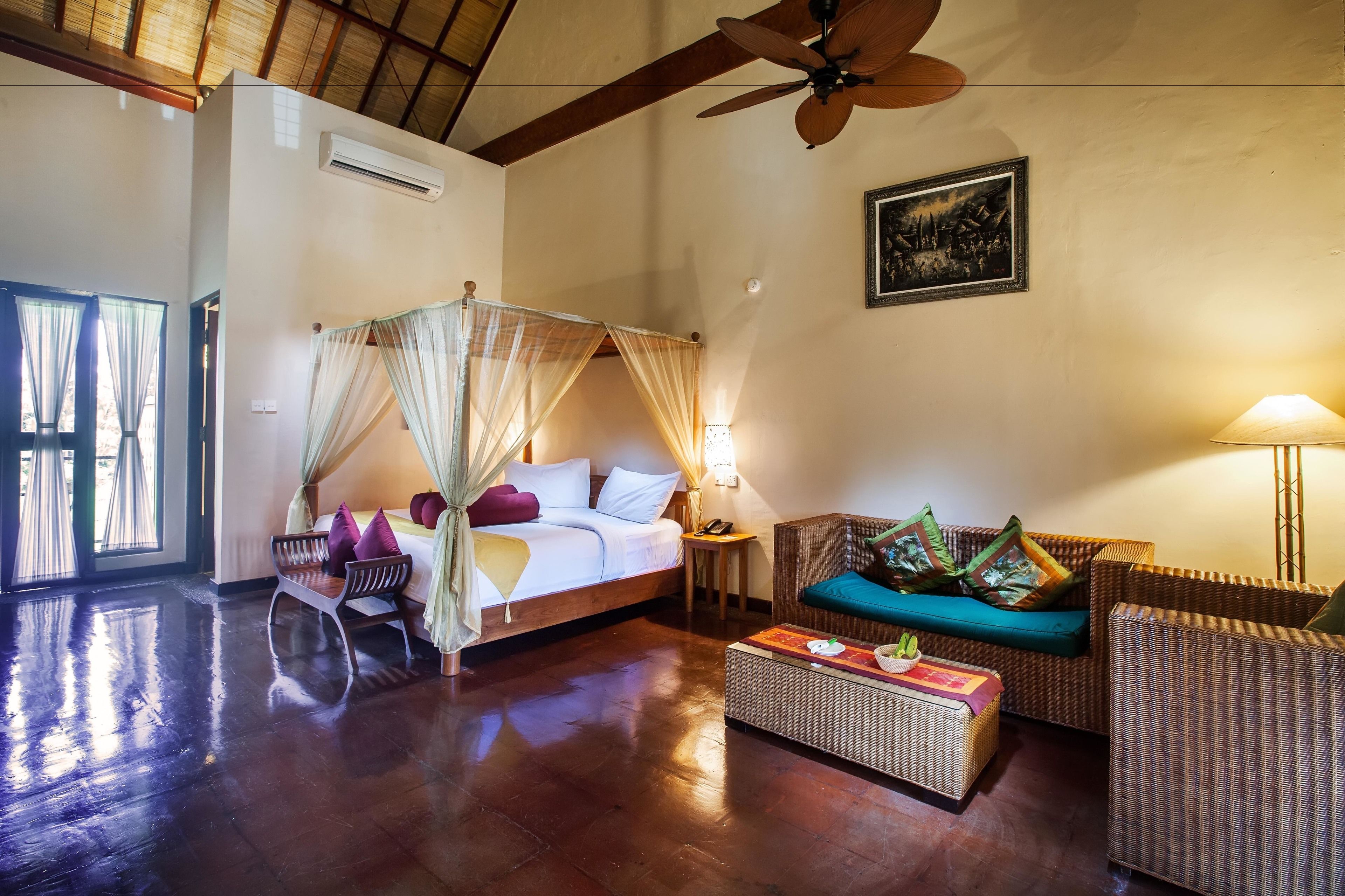 Une pièce comprenant un lit, un canapé, une table basse et un ventilateur de plafond.