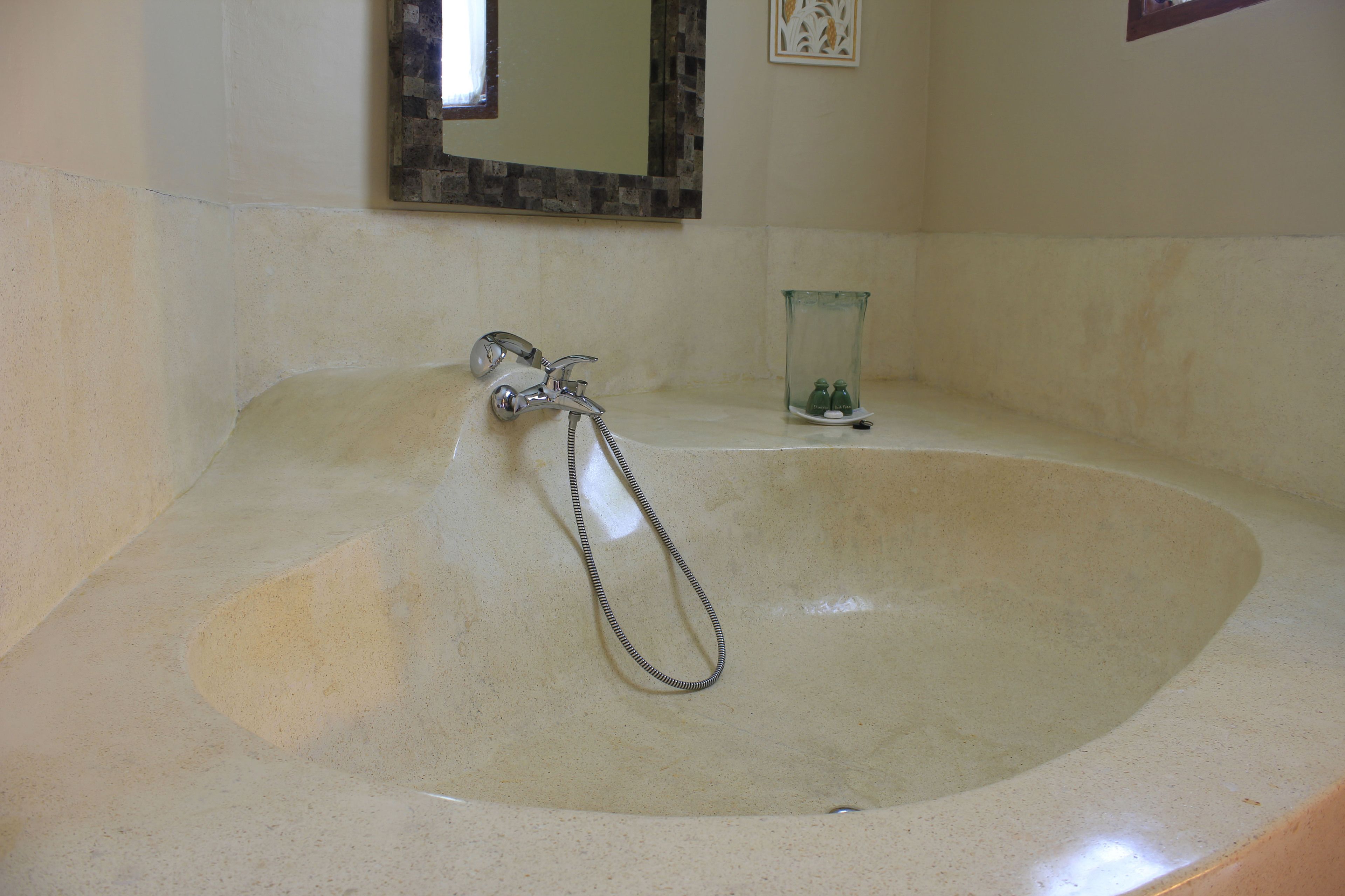 Une salle de bain avec une baignoire, un robinet et un récipient en verre posé sur le comptoir.
