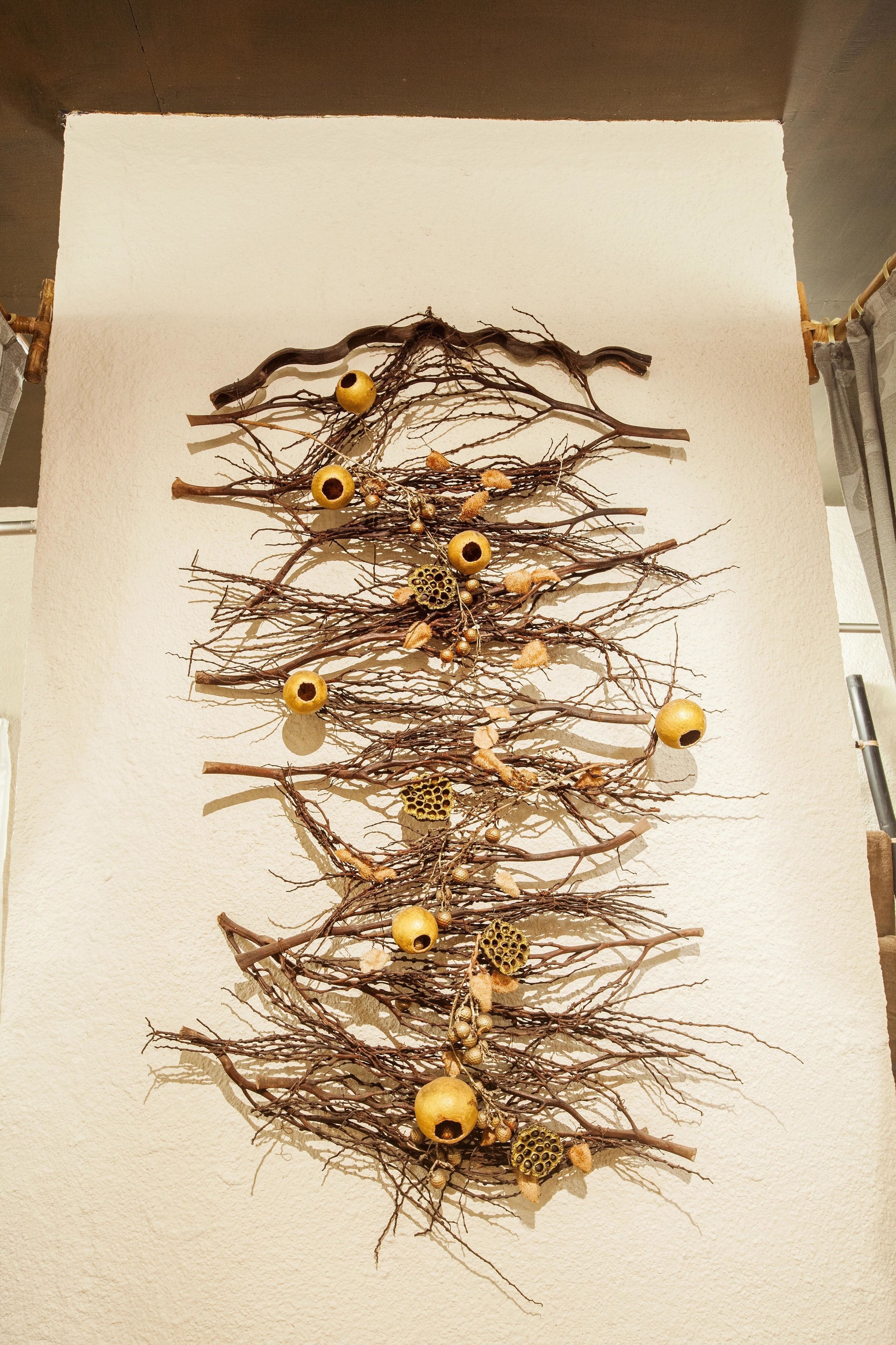 A wall-mounted art installation with branches and golden ornaments.
